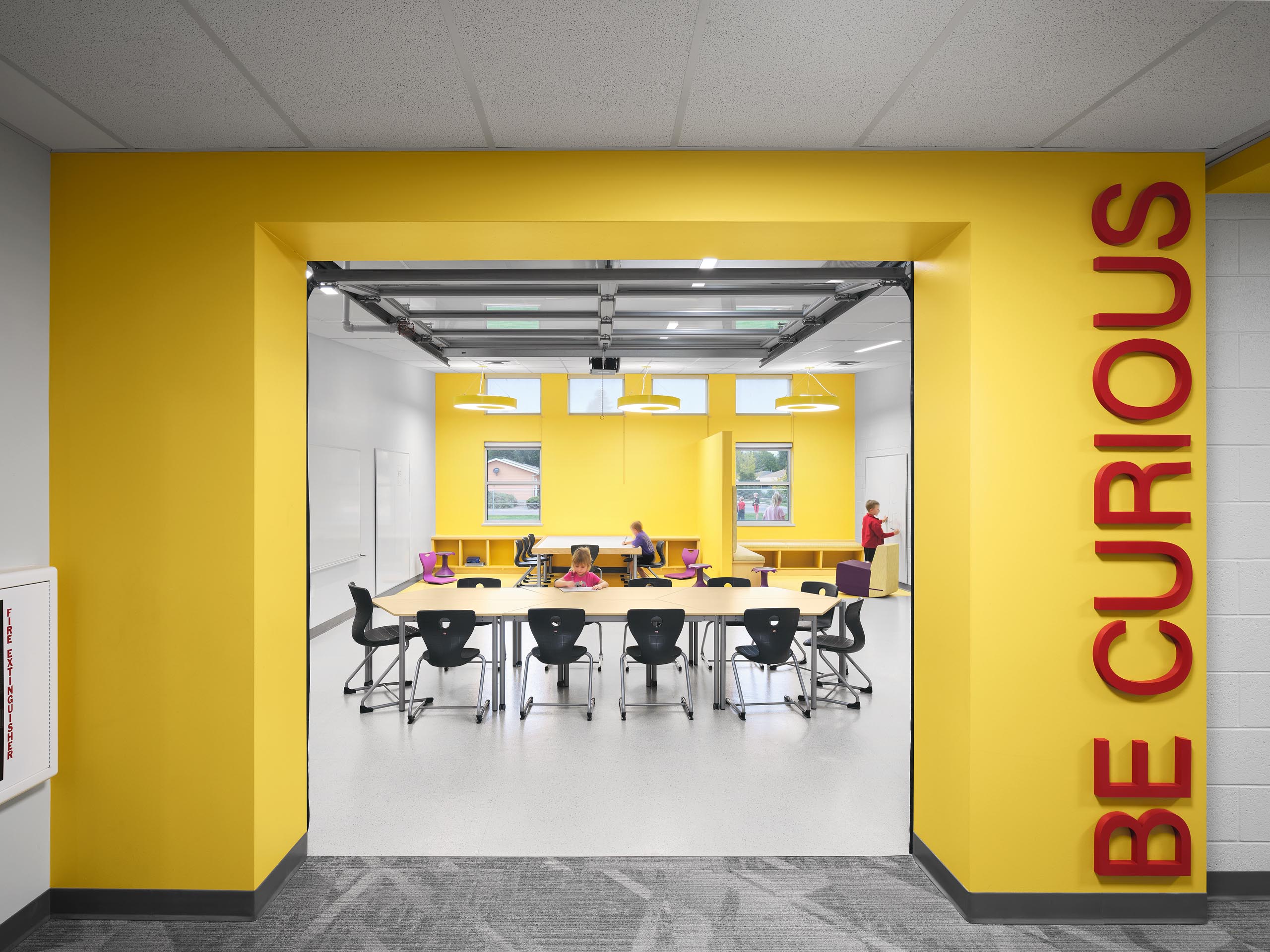 Architectural photography by Warren Diggles. Eaton Elementary students in room with bold yellow colors and overhead door opening. K-12 remodel project by RB+B Architects and FCI Constructors.